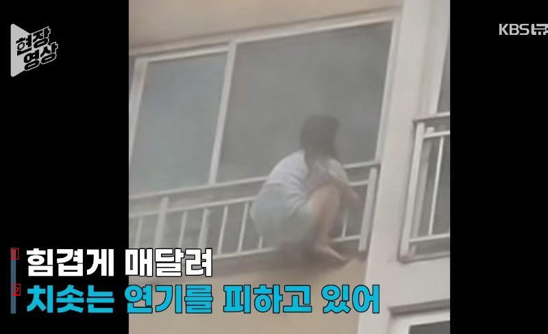 a girl hanging from a railing on the 11th floor of an apartment building