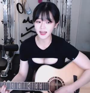 QWER leader Cho Dan plays guitar and sings, his cleavage drawing attention