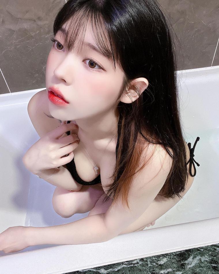 BJ Yudi's cleavage seen from above while sitting in the bathtub wearing a black bikini