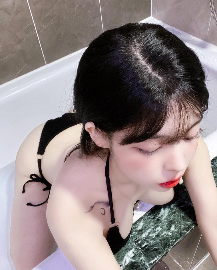 BJ Yudi's cleavage seen from above while sitting in the bathtub wearing a black bikini